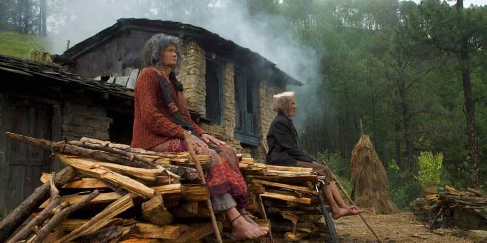 Elderly Indian woman sitting in front of mountain hut on funeral pyre