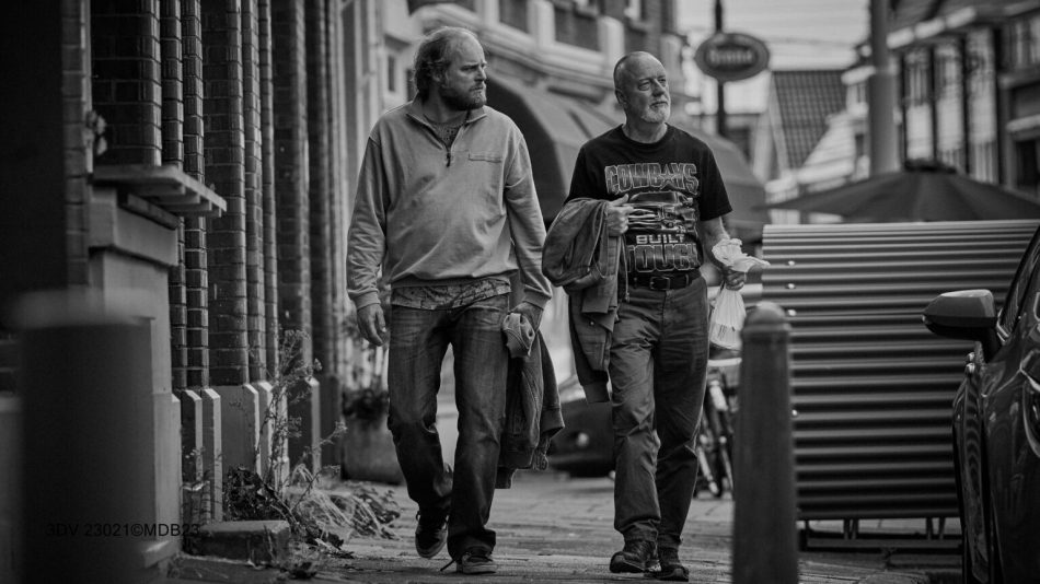 Adult son and his father walking through town, b/w