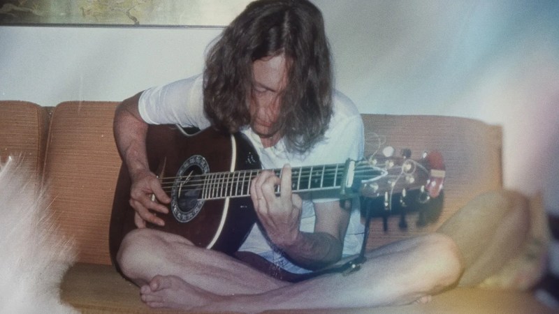 Photo of John Lennon playing Guitar at home